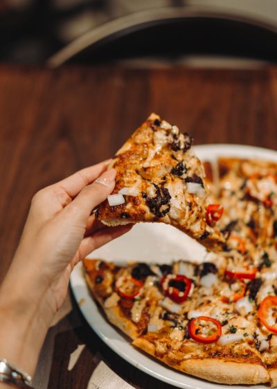 Hand holding a slice of gourmet pizza at Pi Bar, promoted by Luma Creative, a San Francisco social media marketing agency