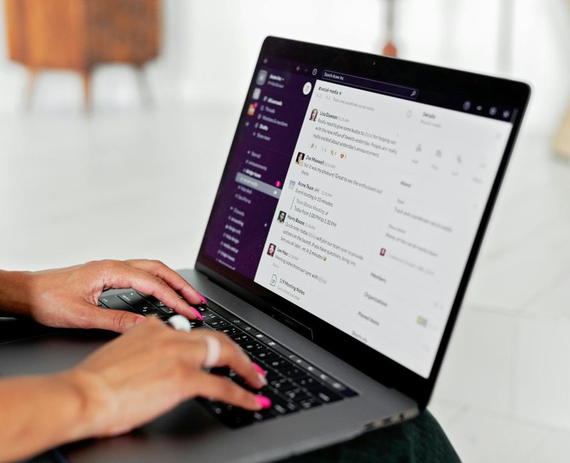 Person managing freelancers by typing messages on Slack app on a laptop